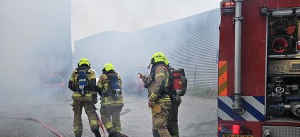 Brandweermannen in pak die staan in de rook omdat zij een brand gaan blussen.