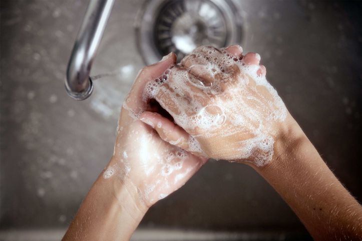 Twee handen worden gewassen met zeep boven een gootsteen